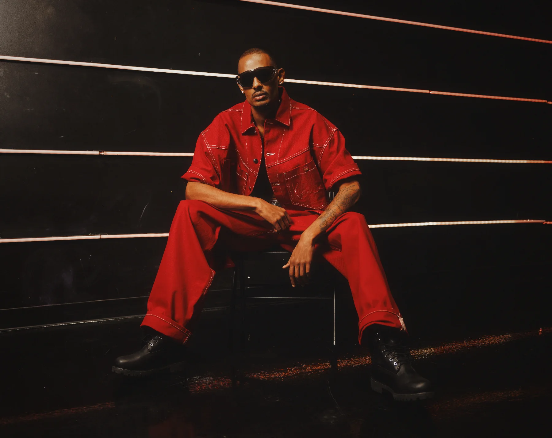 NIJO shot by Calvin G — seated, custom Red Canvas Karl Kani look