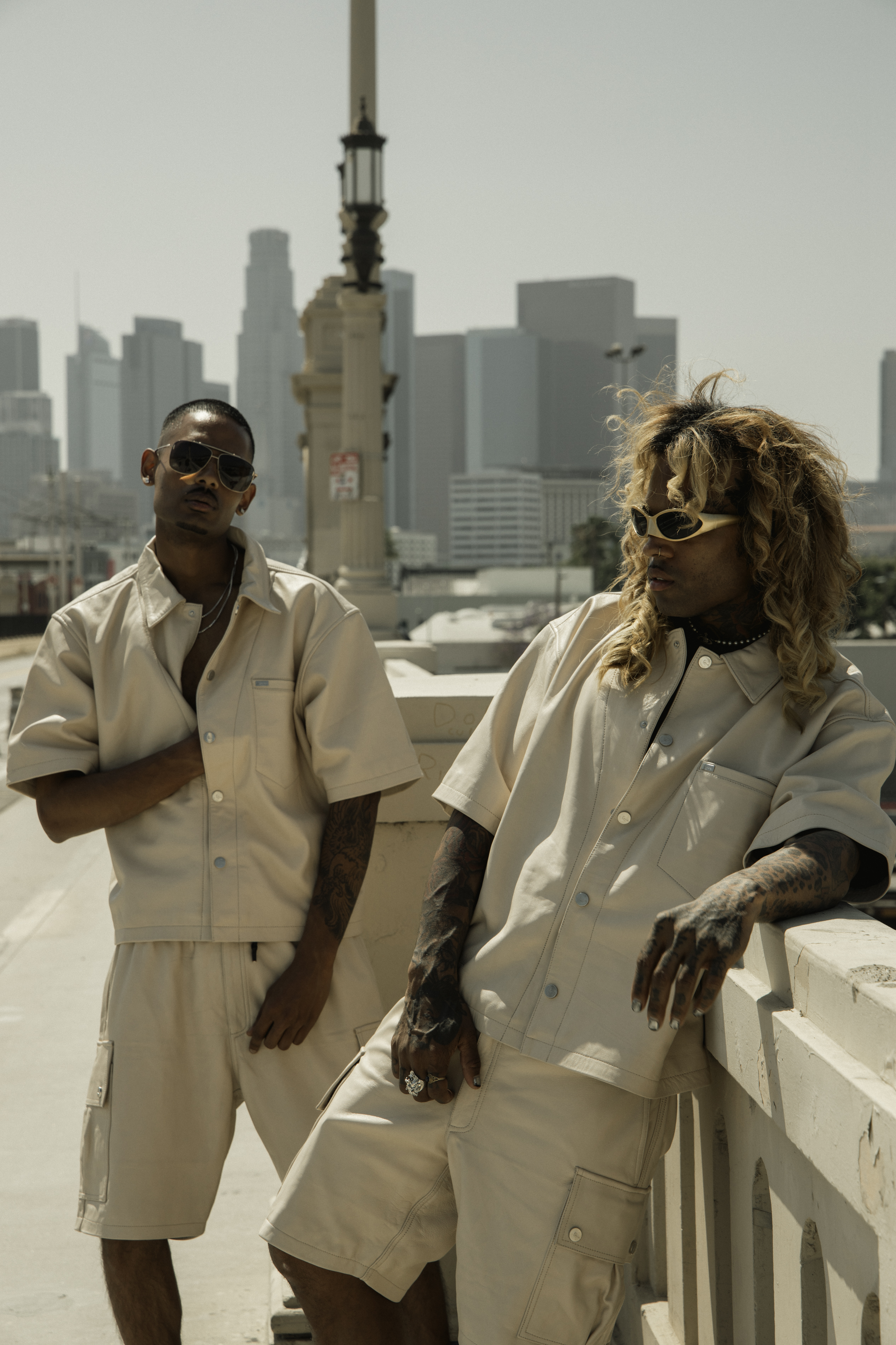 NIJO and counterpart in beige Karl Kani Ford leather shirts and Mace leather cargo, Los Angeles skyline behind