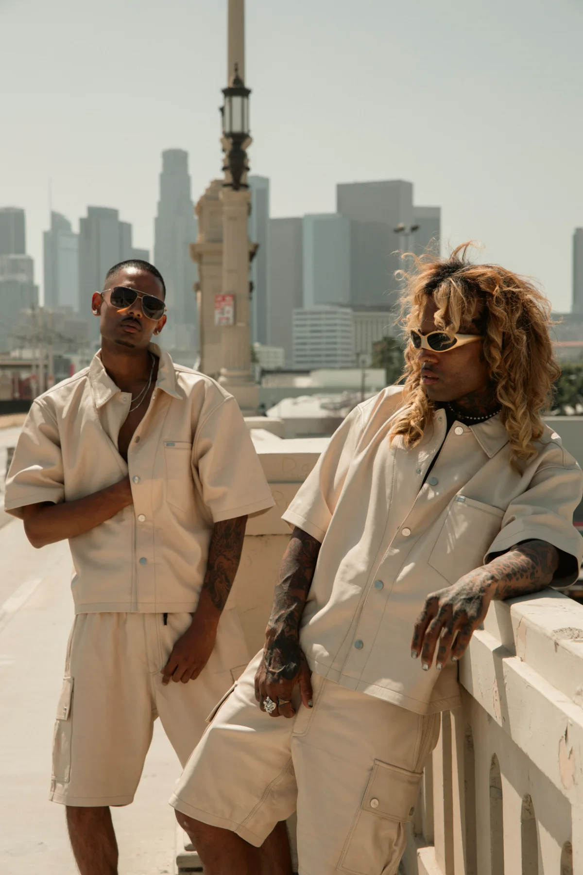 NIJO and counterpart in beige Karl Kani Ford leather shirts and Mace leather cargo, Los Angeles skyline behind