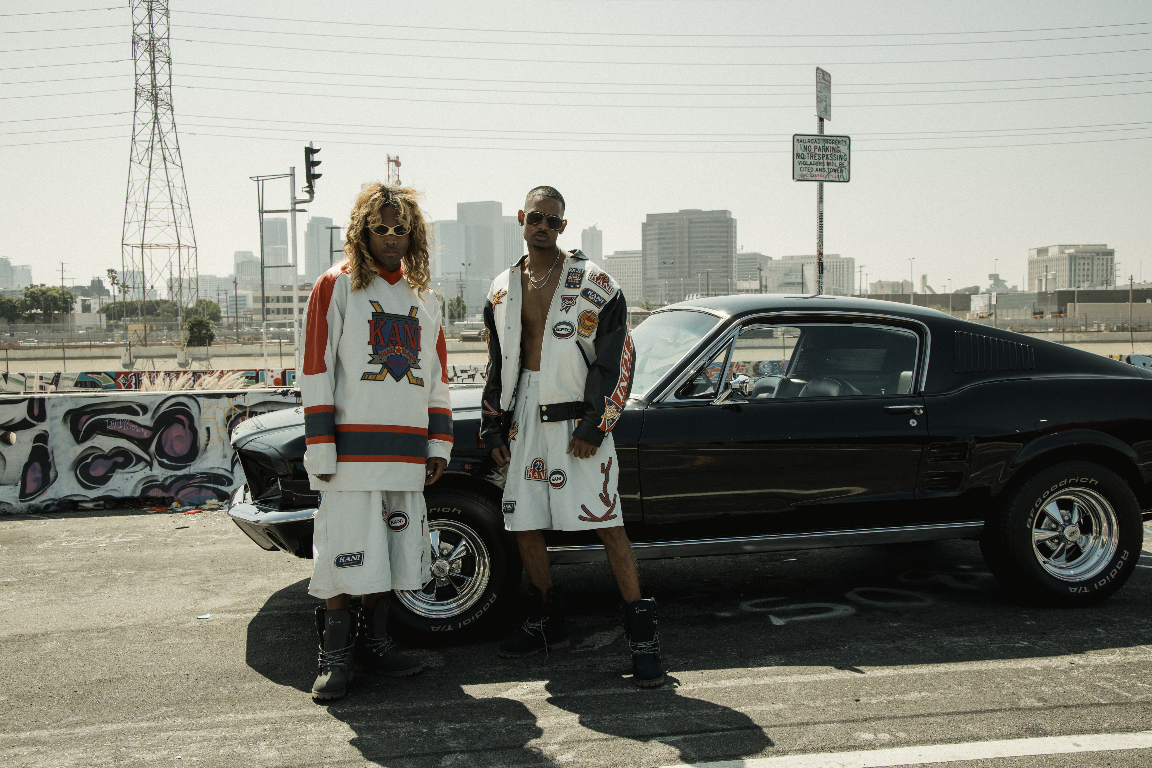 NIJO on the phone — white Karl Kani Jeans tee, Frankfurt towers behind