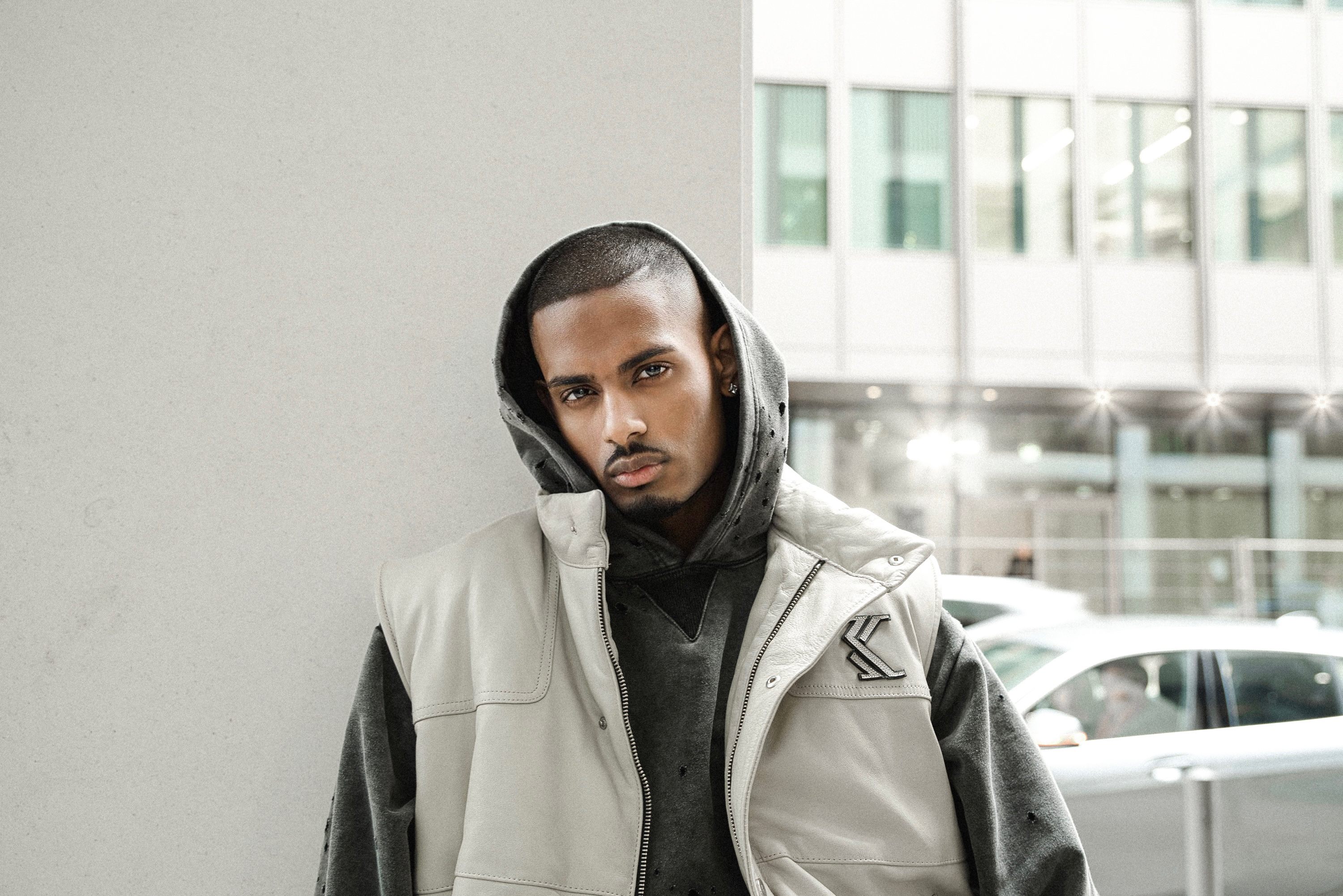 NIJO leaning, leather puffer vest, hooded, white concrete plaza