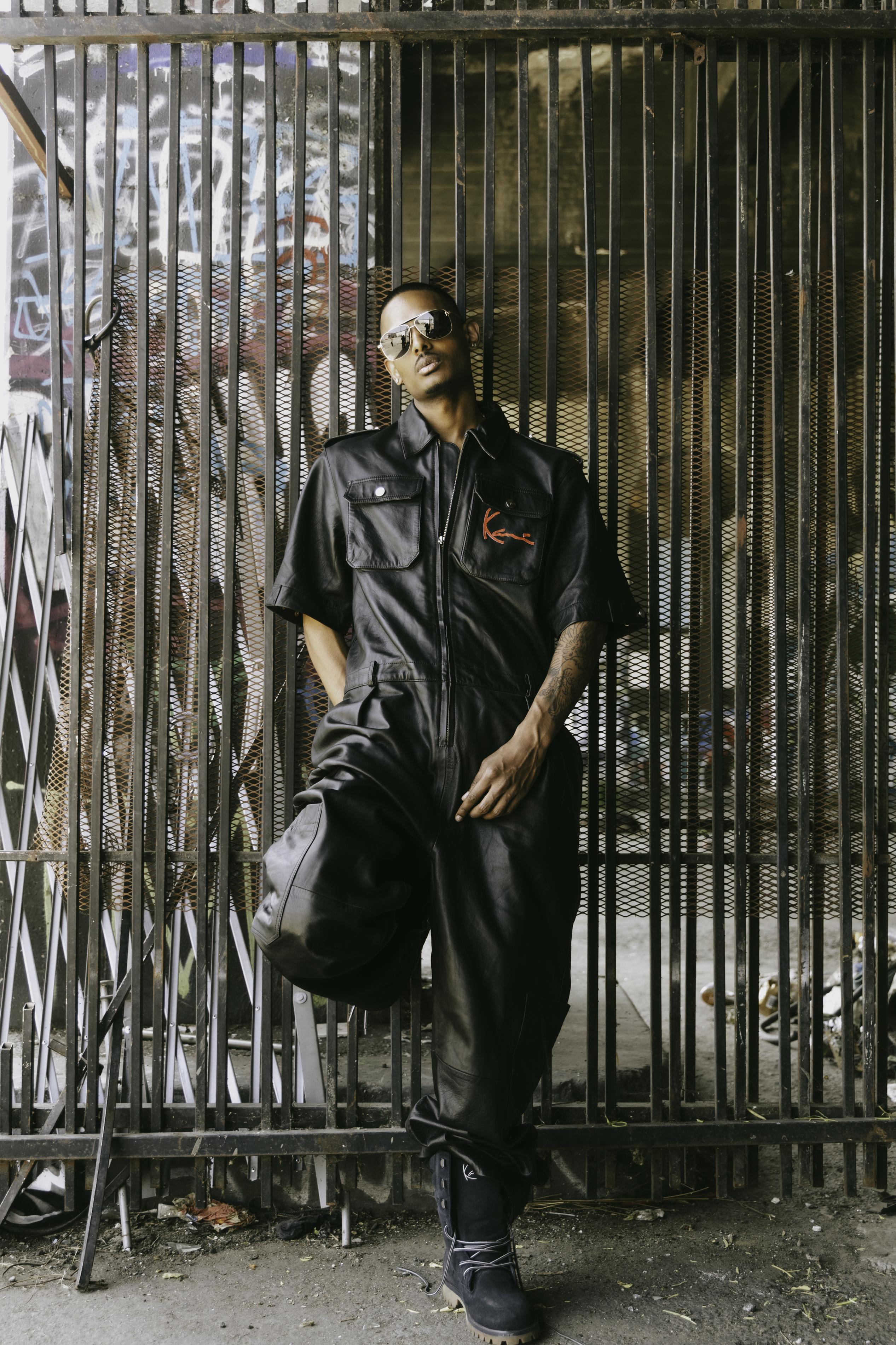 NIJO and counterpart in matching black leather moto coveralls, graffiti wall
