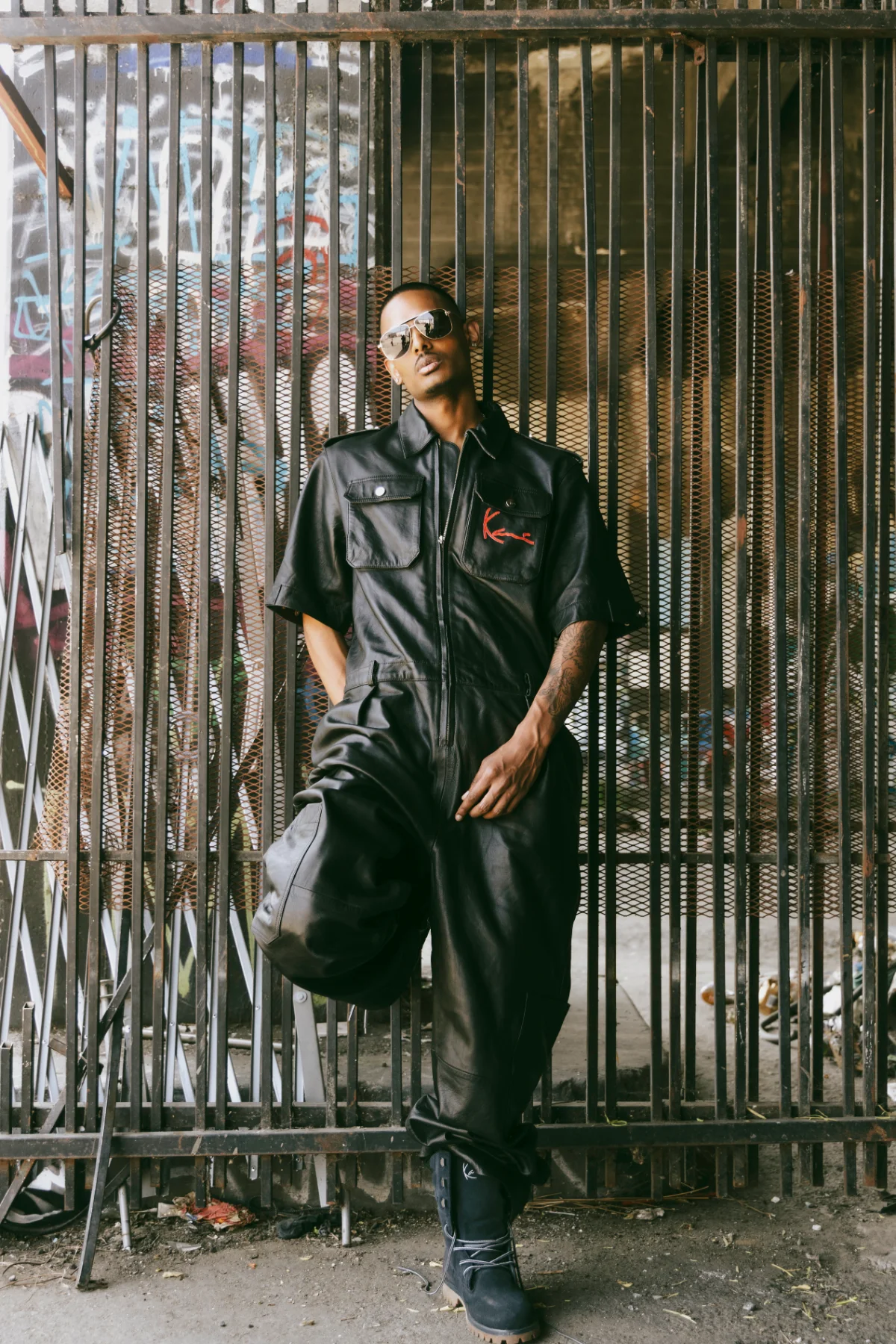 NIJO and counterpart in matching black leather moto coveralls, graffiti wall